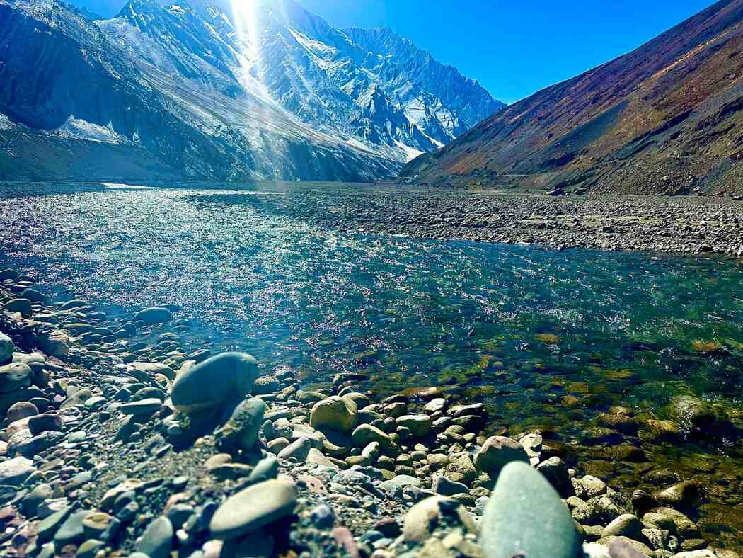 The Pin River rushing over rocks and pebbles, surrounded by towering Himalayan peaks